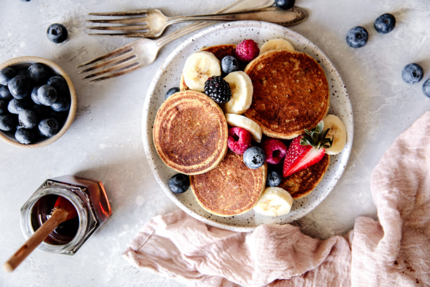 assiette de pancakes et fruits rouges fraise framboises et myrtilles avec du miel pour un petit dejeuner