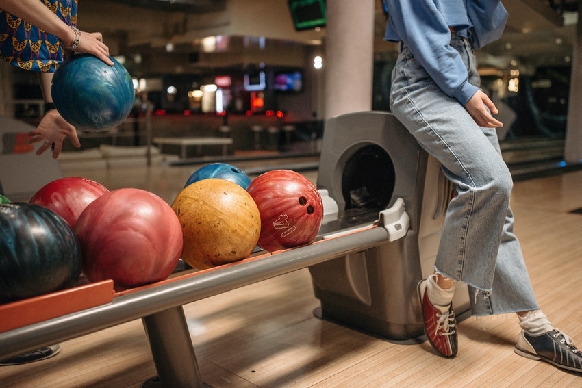 femme assise sur presentoir de boules de bowling