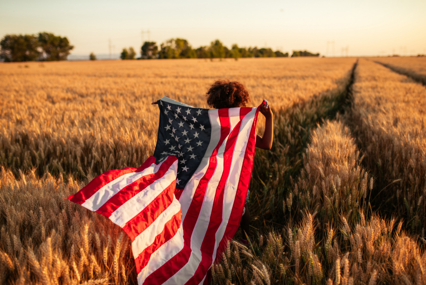 femme qui court dans un champ avec drapeau americain