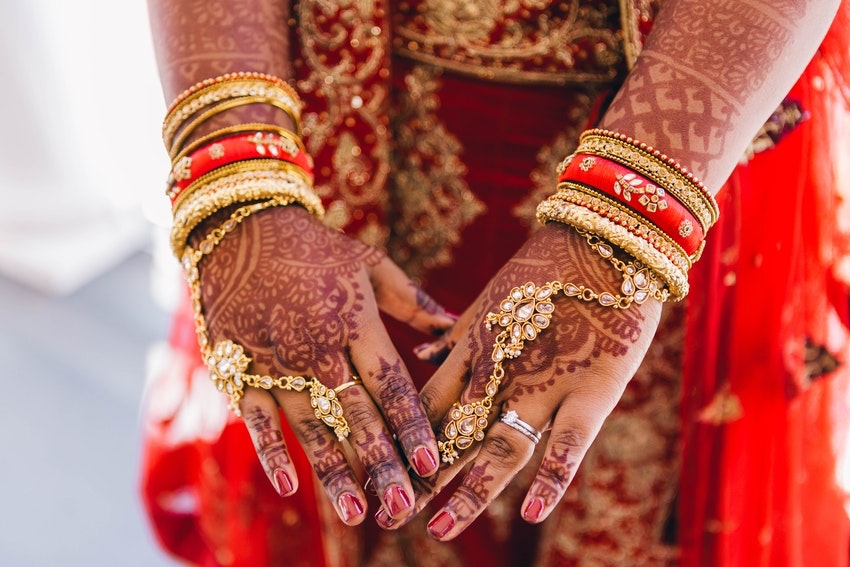 mains dune femme tatouee au henne avec bijoux dores et tenue rouge