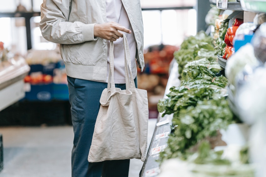 corps d'homme avec un tote bag dans un supermarché devant des salades