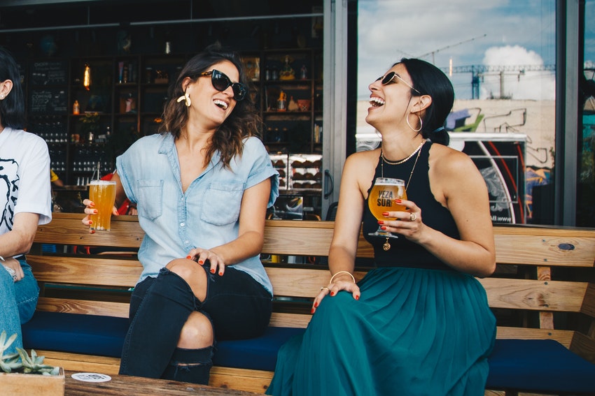 deux femmes qui rient sur un banc un verre à la main