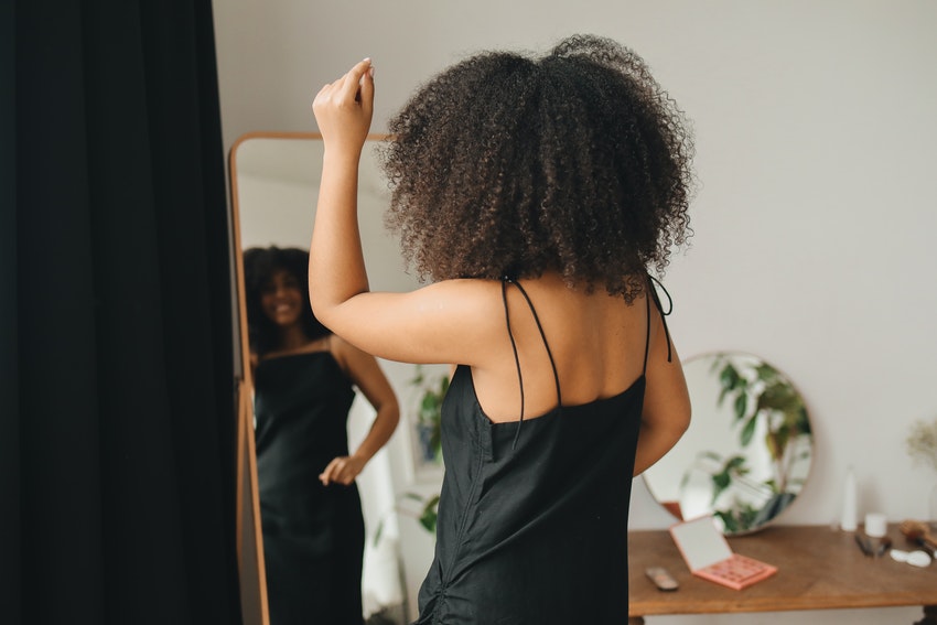 femme devant un miroir en nuisette le bras levé