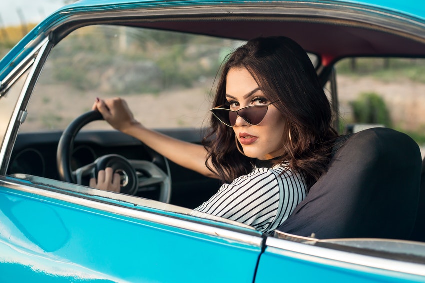 jeune femme au volant d une voiture bleu regardant par son epaule