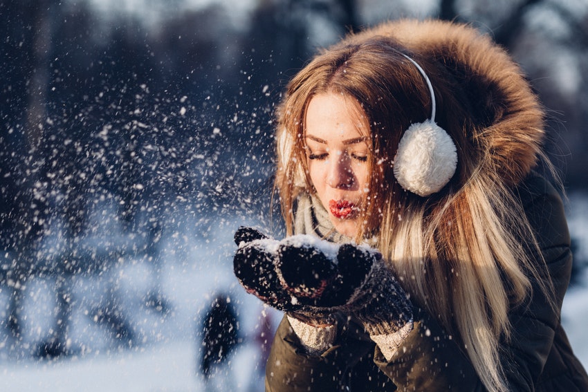 jeune femme soufflant des flocons de neige