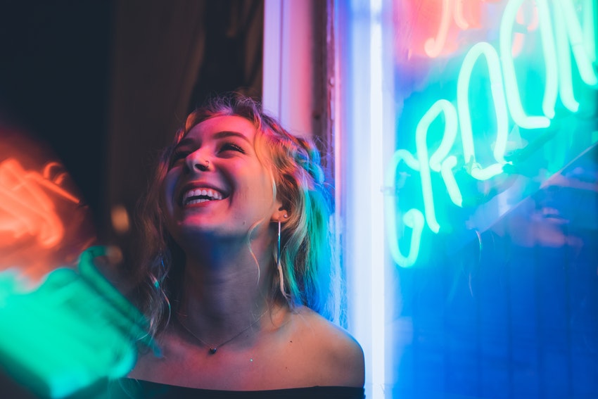 jeune femme souriante illuminee par un neon