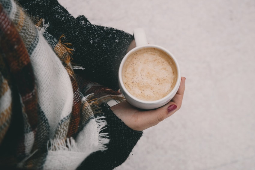 tasse de cafe chocolat tenue par une femme au dessus de la neige