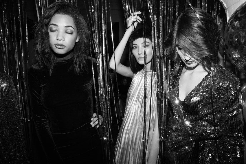 trois filles en tenues de soiree sous un rideau paillette en noir et blanc