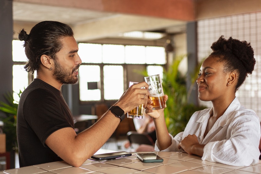 un homme et une femme assis dans un bar un verre à la main