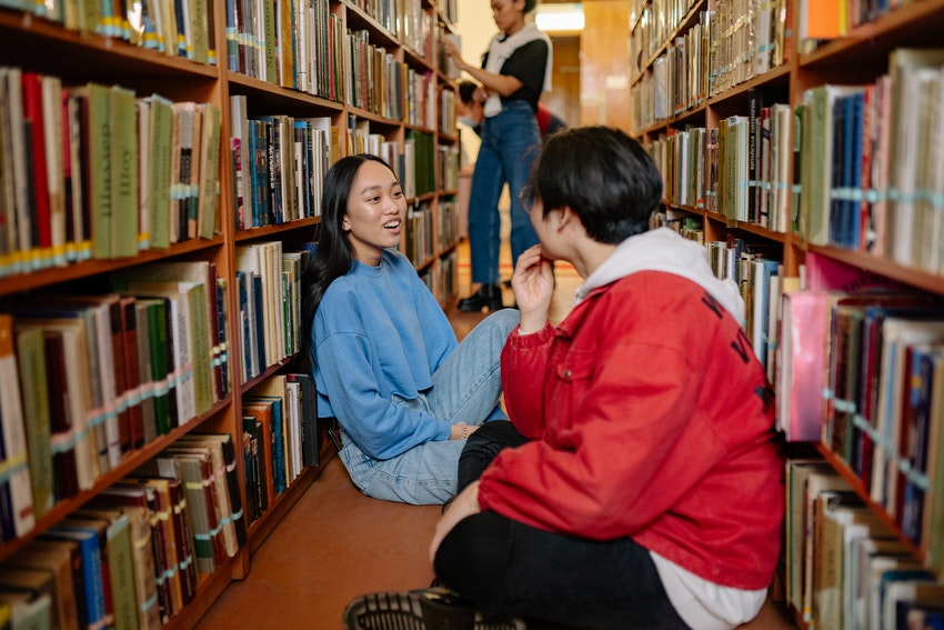 une garcon et une fille assis dans les couloirs d'une bibliotheque