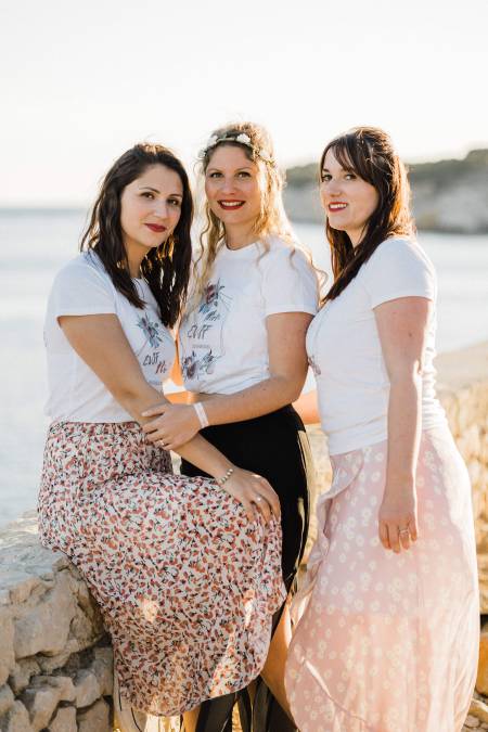 3 femmes en front de mer habillées de couleurs douces 