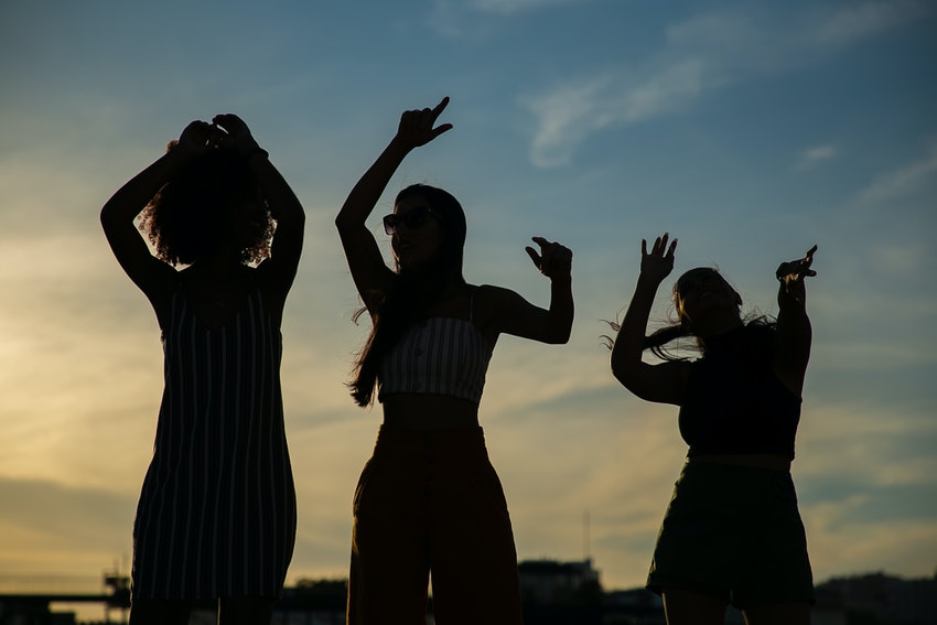 trois jeunes femmes dansant sous le couche du soleil