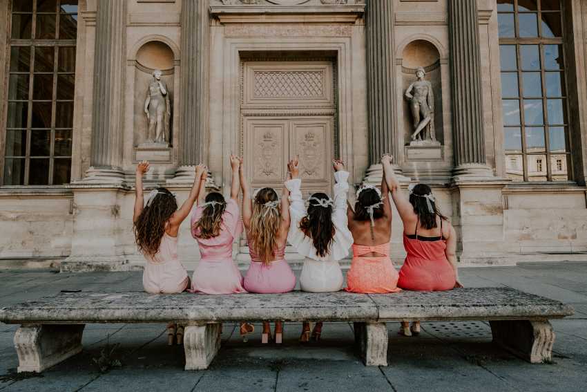 groupe de copines en robes roses assisent sur un banc a paris