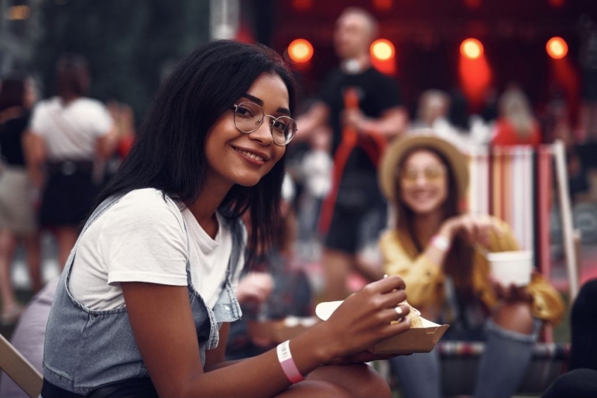 jeune femme assise devant une scene de concert entrain de manger