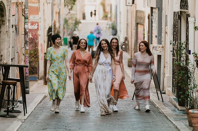 Groupe de femmes élégantes marchant dans une rue pittoresque d'Aix-en-Provence lors d'un EVJF.