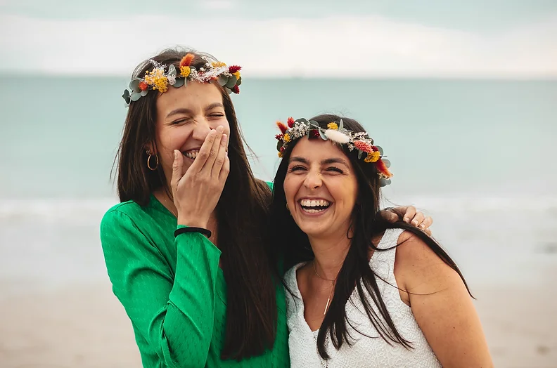 Deux femmes souriantes avec des couronnes de fleurs célébrant un EVJF sur la plage de La Baule.