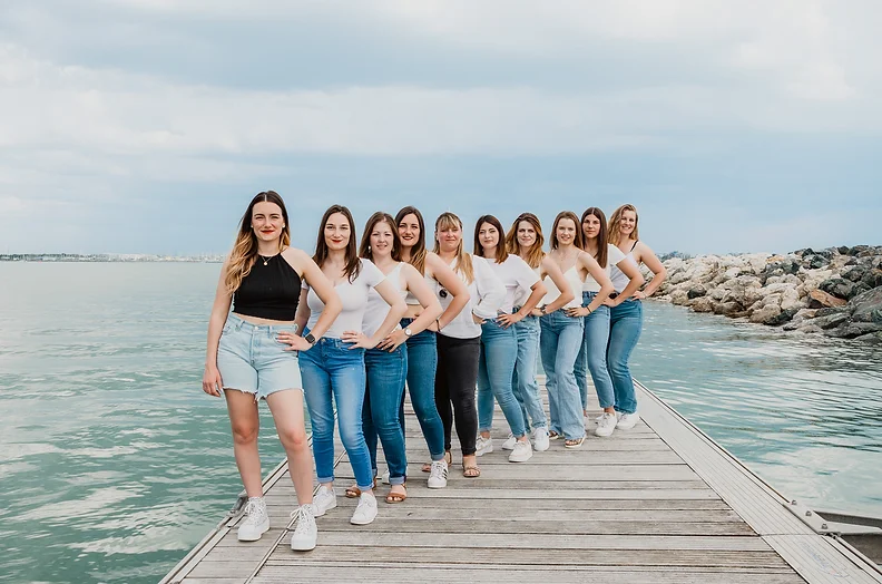 Groupe de femmes célébrant un EVJF à La Rochelle, posant sur un ponton avec l'océan en arrière-plan.