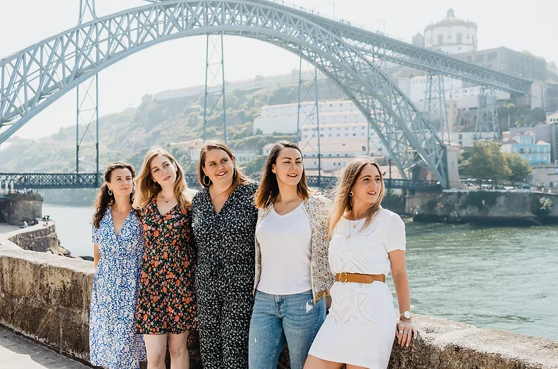 Un groupe de femmes célébrant un EVJF devant le Pont Dom Luís I à Porto, avec le Douro en arrière-plan.