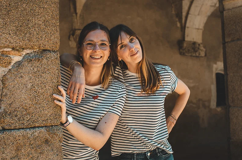 Deux femmes en marinières souriant, posant devant des pierres anciennes dans le centre historique de Rennes lors d'un EVJF.