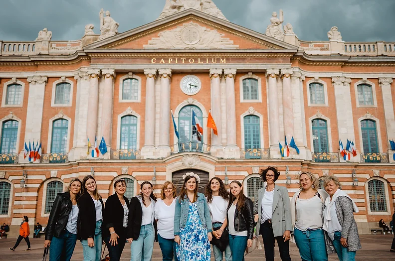 Groupe de femmes célébrant un EVJF à Toulouse, posant devant le Capitole, bâtiment emblématique de la ville.