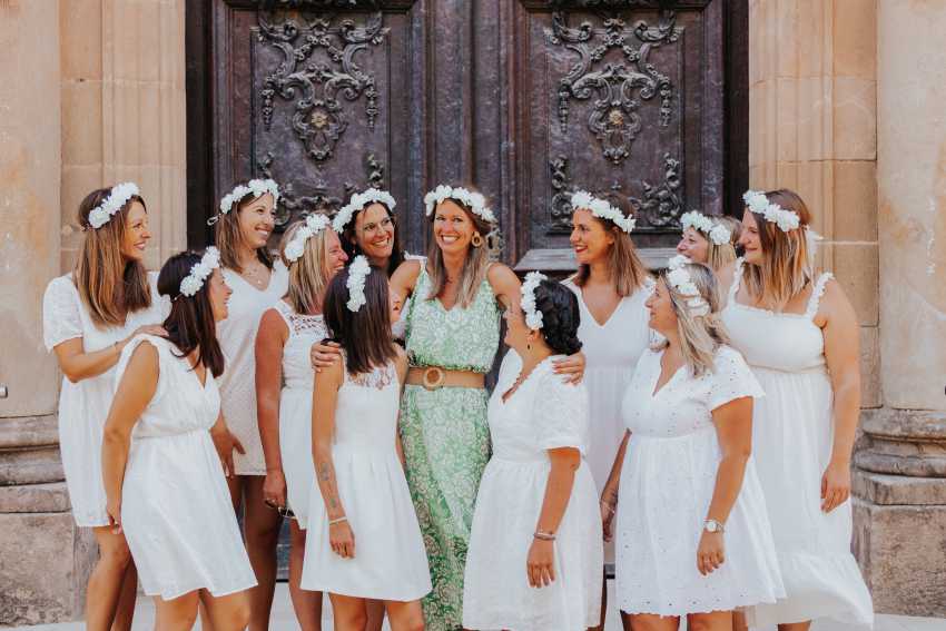 Groupe de femmes vêtues de blanc avec des couronnes de fleurs célébrant un EVJF à Tours, devant une porte ancienne ornée