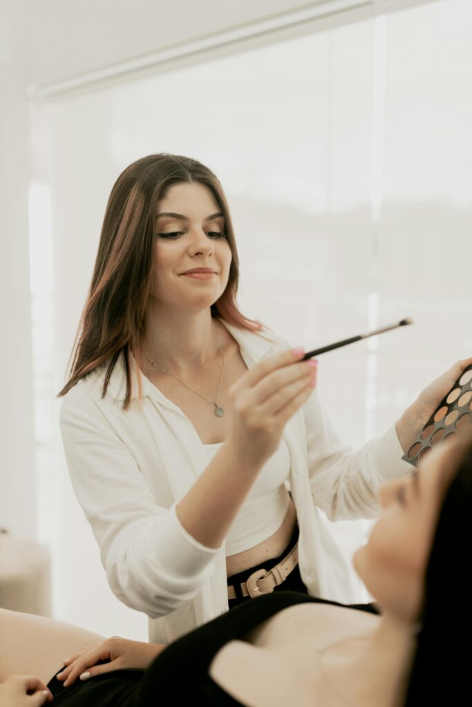 Maquilleuse à Lyon maquillant la future mariée pendant un atelier beauté EVJF – activité mise en beauté entre amies.