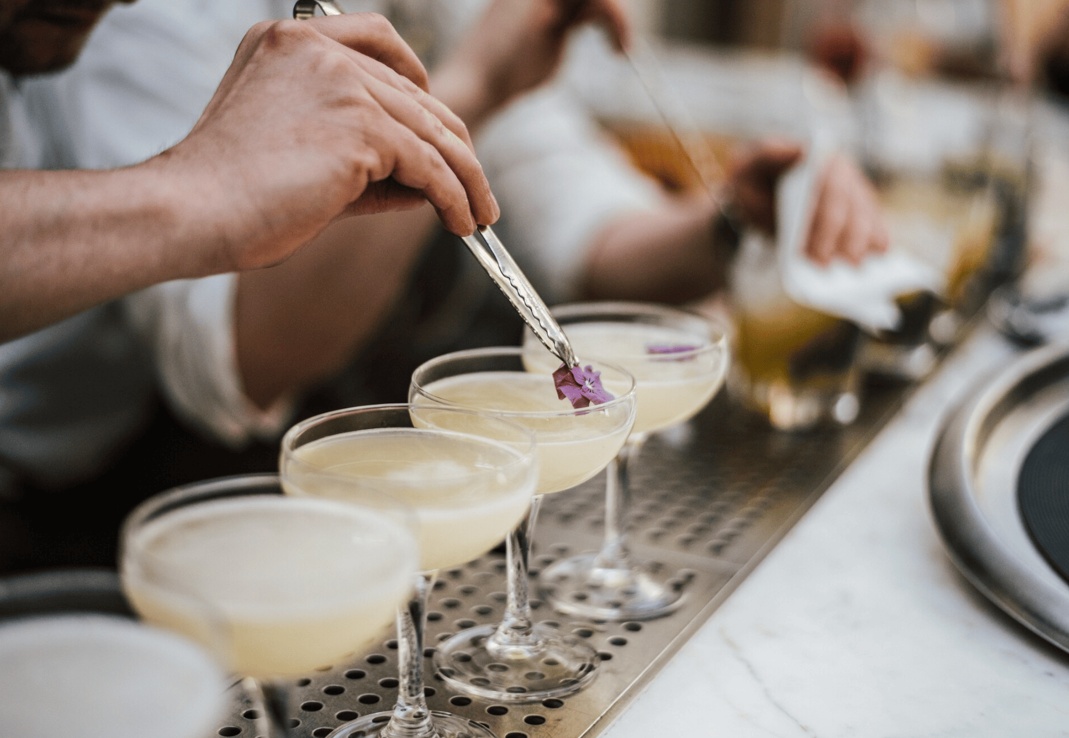 Atelier cocktail EVJF à Toulouse, main d’une participante décorant un cocktail avec fruits et herbes fraîches, ambiance créative et festive