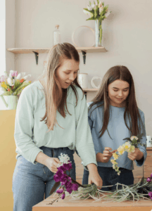 Atelier floral EVJF à Strasbourg, groupe de femmes créant des couronnes de fleurs dans une ambiance douce et créative