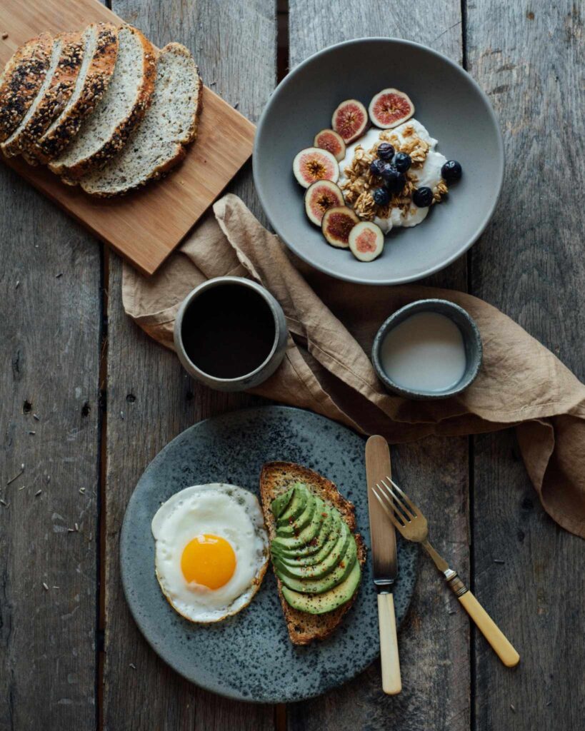 Petit-déjeuner raffiné avec tartine d’avocat et œuf au plat, bol de yaourt aux fruits frais et granola, idéal pour un Brunch EVJF à Marseille.