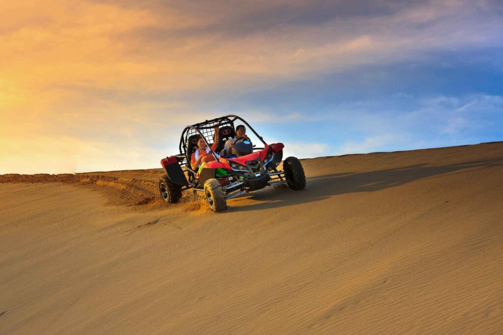 Femmes conduisant un buggy tout-terrain dans le sable au coucher du soleil, lors d’une activité EVJF à Deauville.