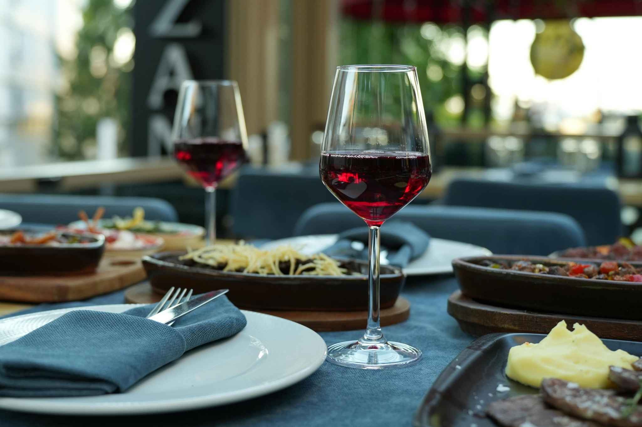 Verres de vin rouge et dîner raffiné lors d’un EVJF, table élégante dressée pour un repas festif entre amies.