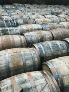 Vue extérieure d’une distillerie traditionnelle en Normandie avec un groupe de femmes en balade dans les vergers, panier de dégustation à la main.

