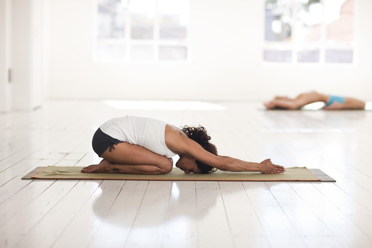 Groupe de femmes pratiquant une séance de yoga en plein air ou dans un studio lumineux à Lille pour un enterrement de vie de jeune fille, ambiance calme et bien-être.