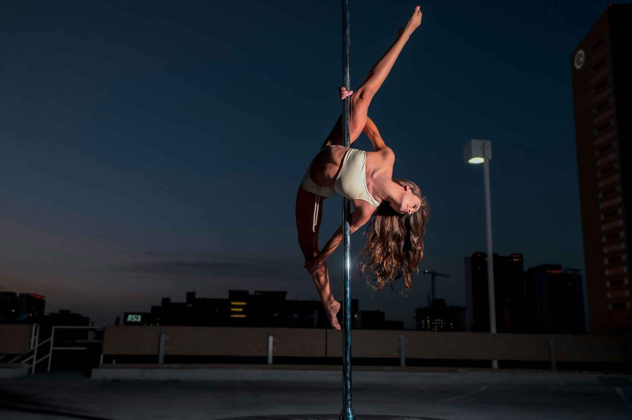 Femme réalisant une figure de pole dance dans une salle proche de Deauville lors d’un EVJF entre amies