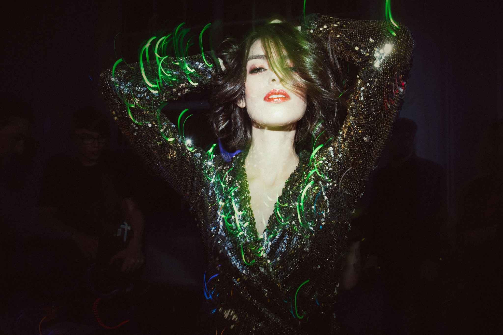 Femme en robe à paillettes dansant au cœur d’une soirée festive avec jeux de lumières colorées