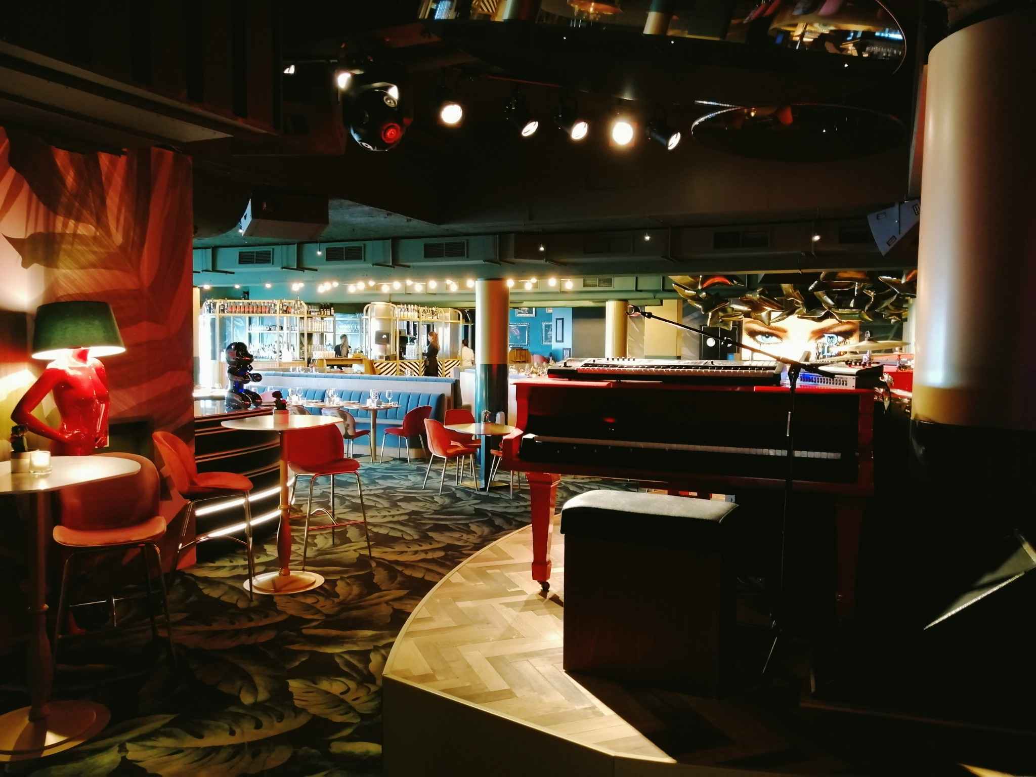 Scène de bar animé avec piano, lumières tamisées et ambiance festive pour une soirée karaoké à Deauville