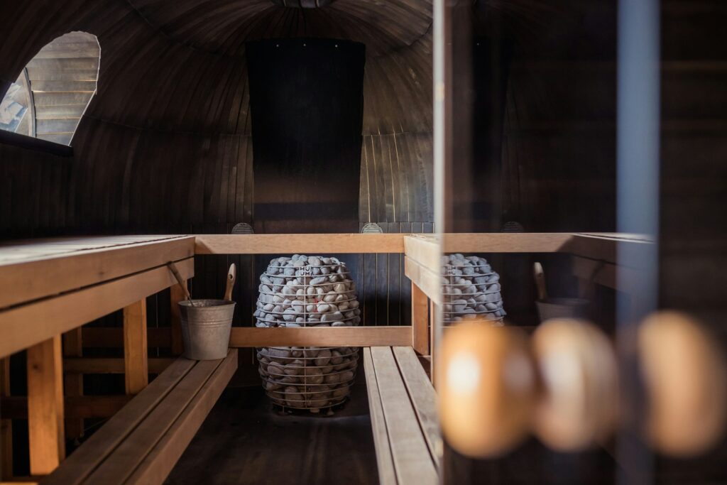 Groupe de femmes assises dans un sauna en bois, souriantes et détendues, lors d’un enterrement de vie de jeune fille à Deauville.

