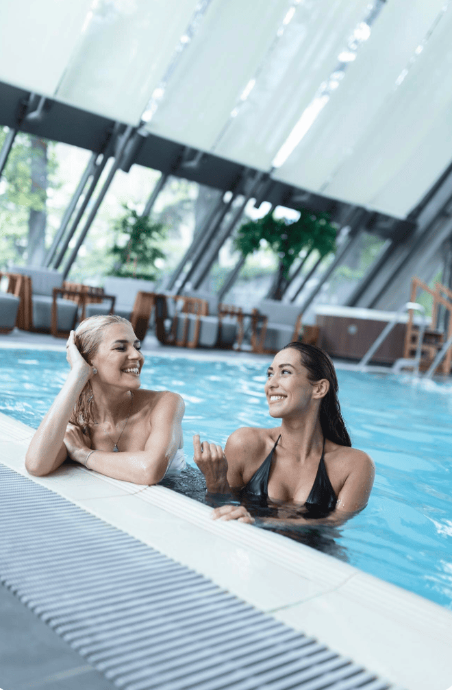 EVJF Spa Toulouse Groupe de jeunes femmes souriantes dans une piscine intérieure de spa à Toulouse, profitant d’un moment de détente pendant un EVJF.