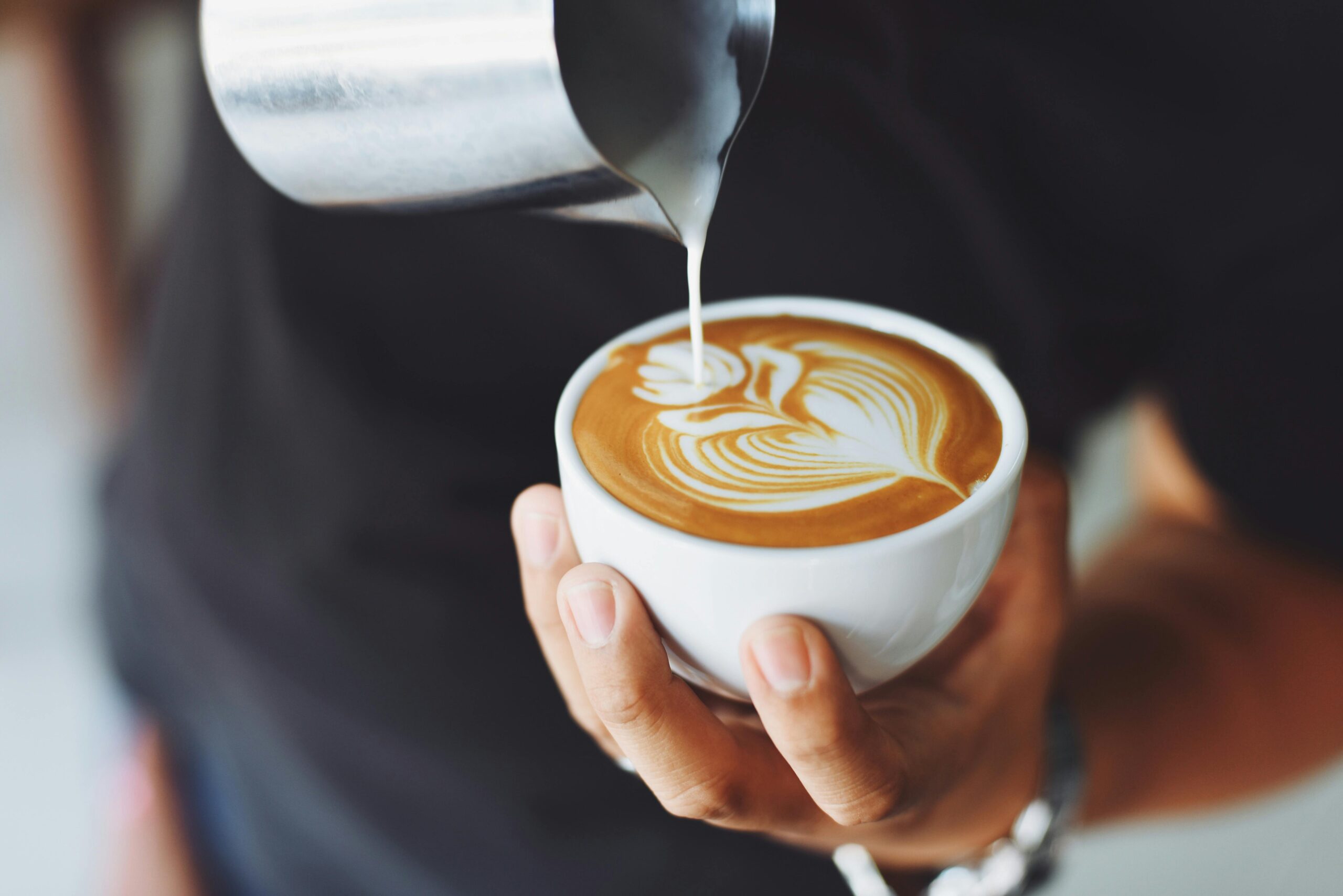Groupe de femmes en train d’apprendre à dessiner des motifs sur du café au lait lors d’un atelier latte art à Lille pour un enterrement de vie de jeune fille, ambiance chaleureuse et créative dans un coffee shop.