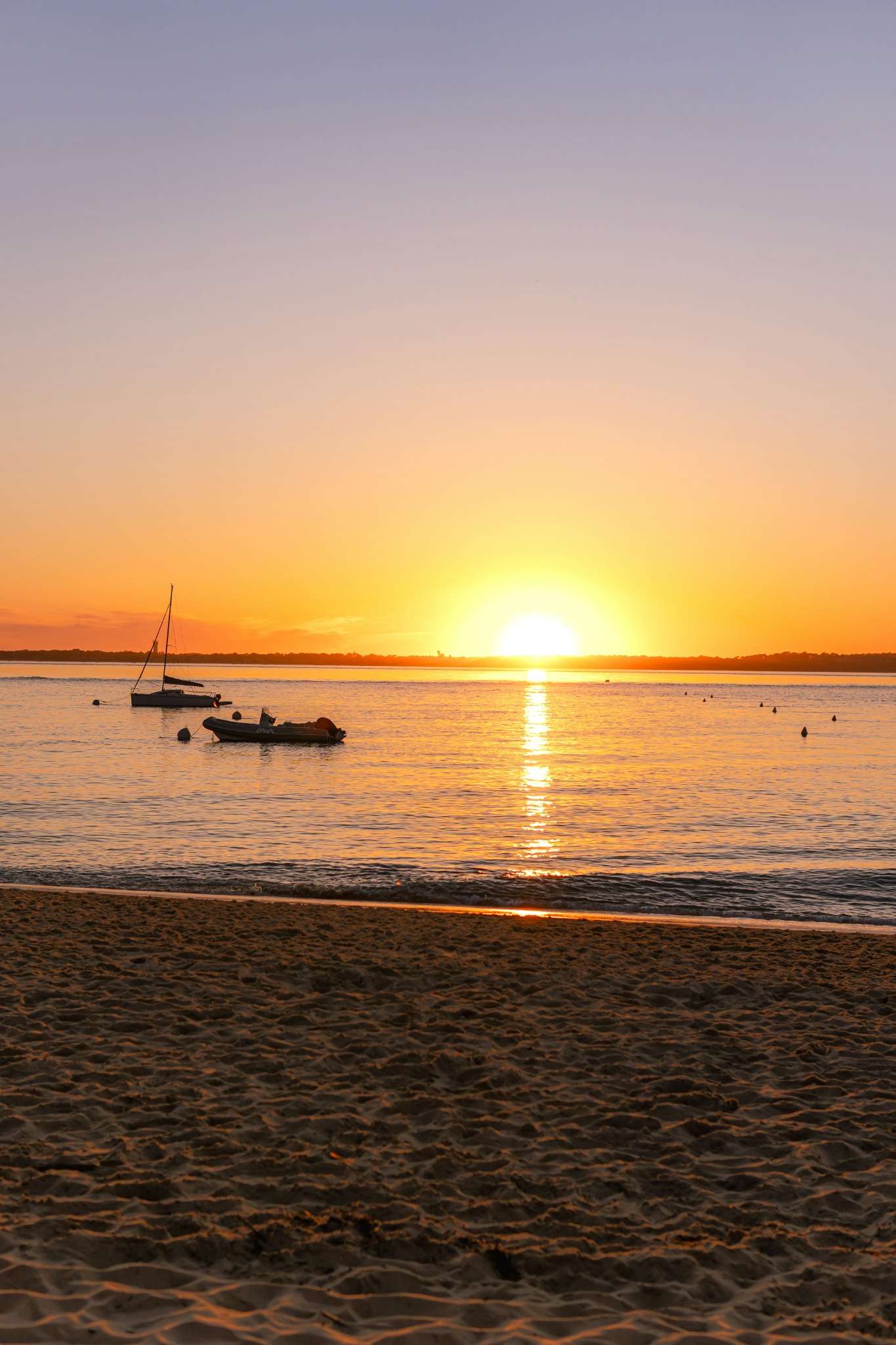 Coucher de soleil sur le Bassin d’Arcachon avec des bateaux à l’horizon, idéal pour une balade en pinasse lors d’un EVJF.