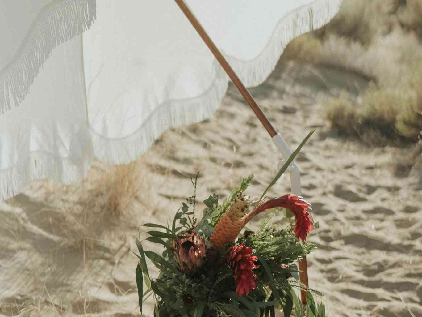 Panier de pique-nique fleuri sous une ombrelle sur une plage ensoleillée à Deauville lors d’un EVJF.