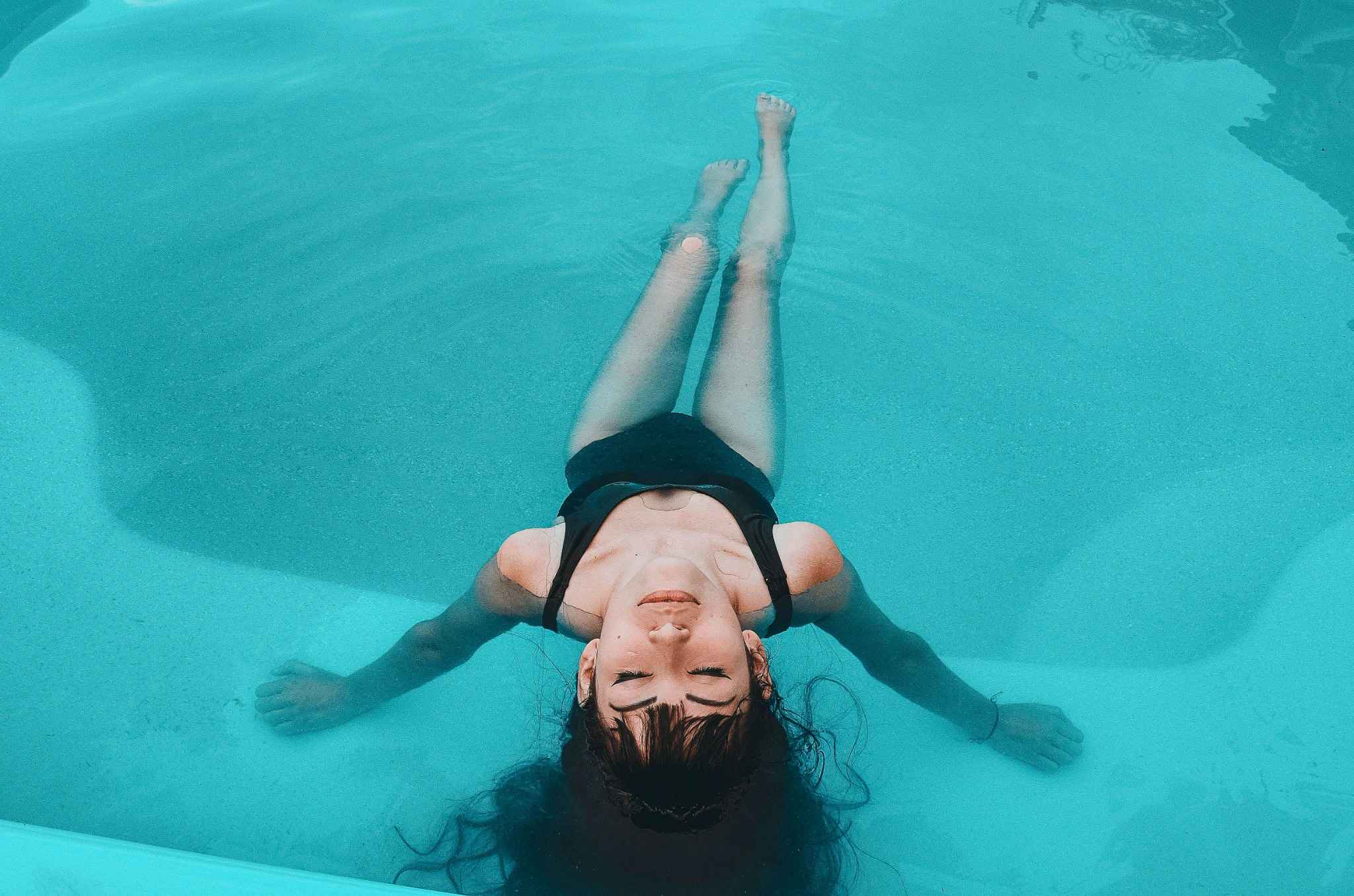 Femme détendue flottant sur le dos dans une piscine turquoise lors d’un moment de relaxation dans un spa privatisé à Deauville