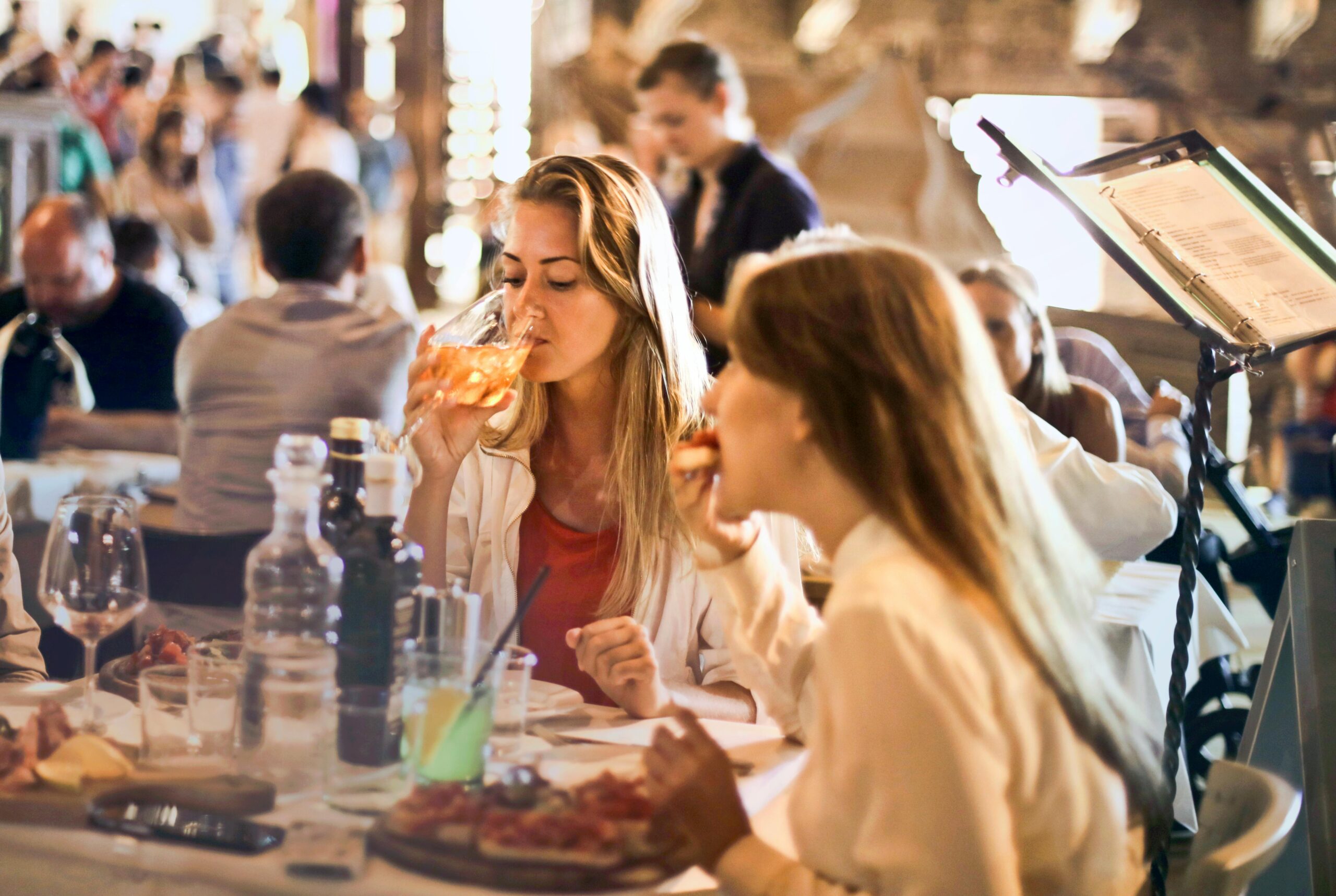 Groupe de femmes souriantes réunies autour d’une grande table joliment décorée pour un dîner d’enterrement de vie de jeune fille à Lille, ambiance festive et chaleureuse.