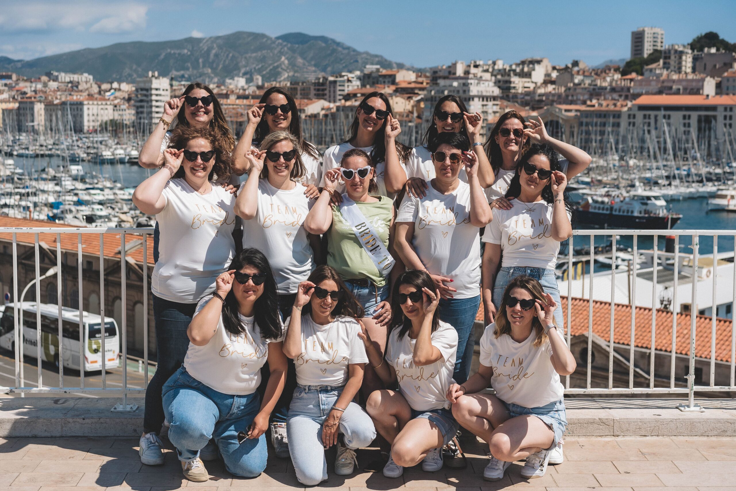 Groupe de femmes posant joyeusement lors d’un shooting photo EVJF à Marseille, avec vue sur la mer.