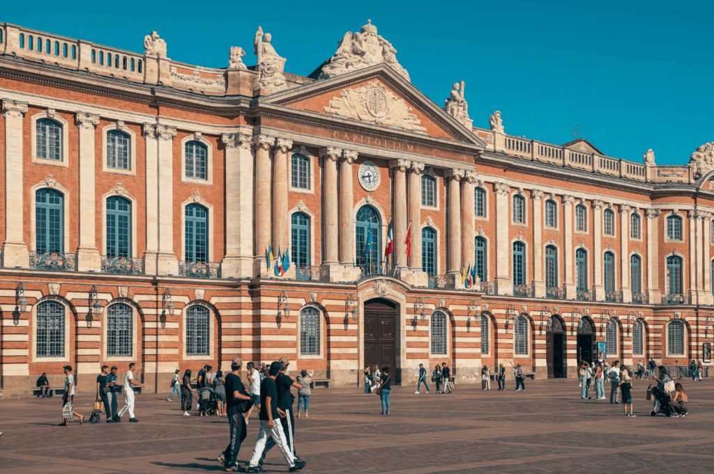 Vue du Capitole de Toulouse sous un ciel bleu, lieu emblématique traversé pendant votre EVJF.
