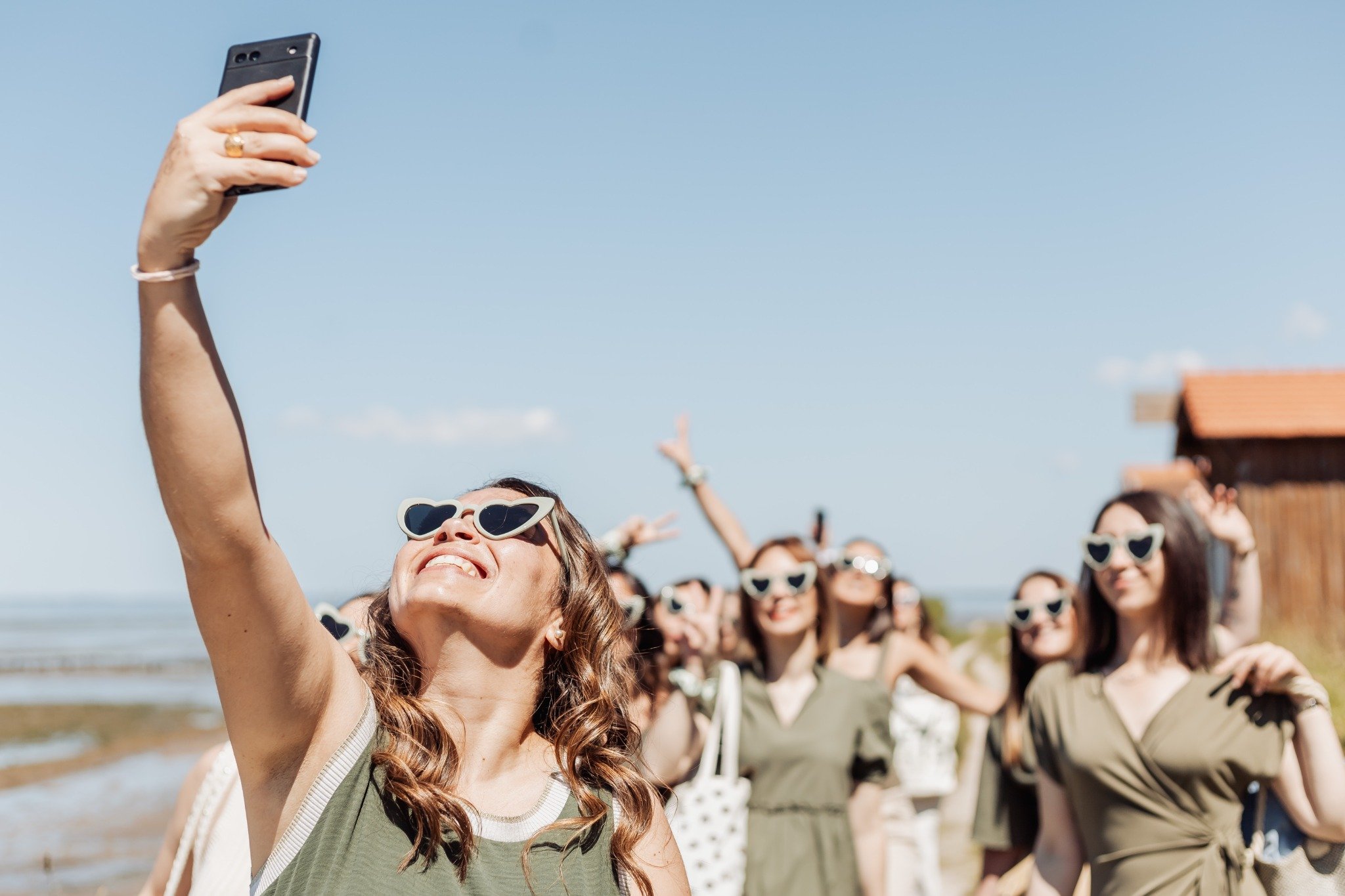 Groupe de femmes souriantes prenant un selfie lors d’une chasse au trésor EVJF à Arcachon, sous le soleil du bassin.
