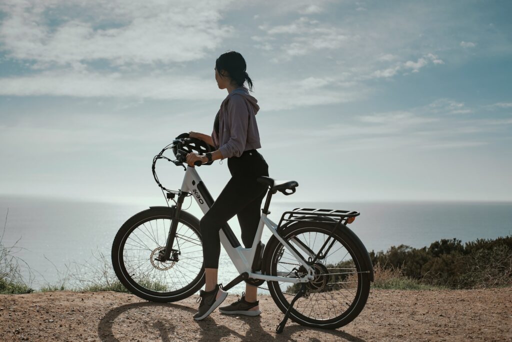 Femme contemplant l’océan depuis les hauteurs de Biarritz avec son vélo électrique blanc, activité EVJF