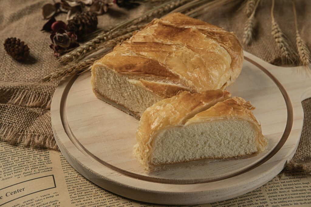alt="Tranche de gâteau basque traditionnel sur planche en bois, spécialité locale de Biarritz"