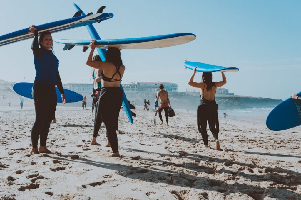 Filles portant leurs planches de surf sur la plage lors d’un EVJF à Biarritz
