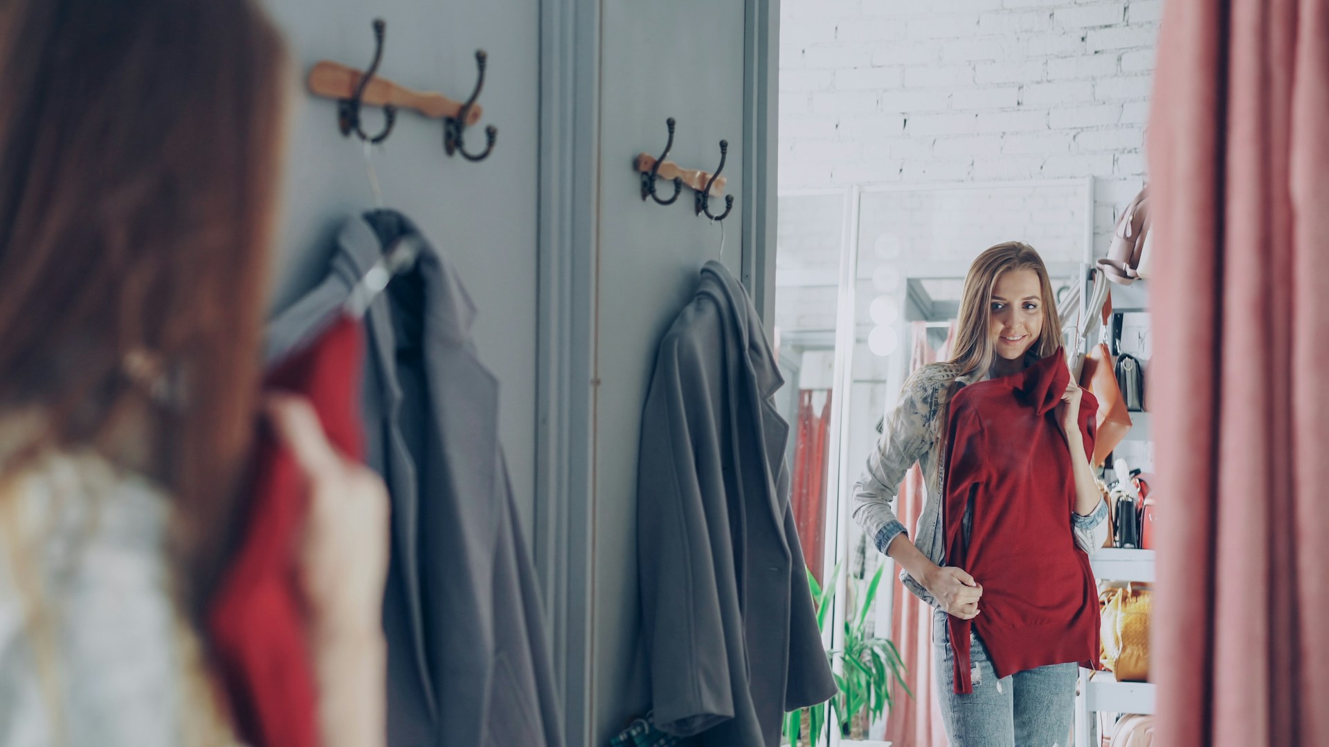 Jeune femme essayant un vêtement rouge pendant une session de shopping EVJF